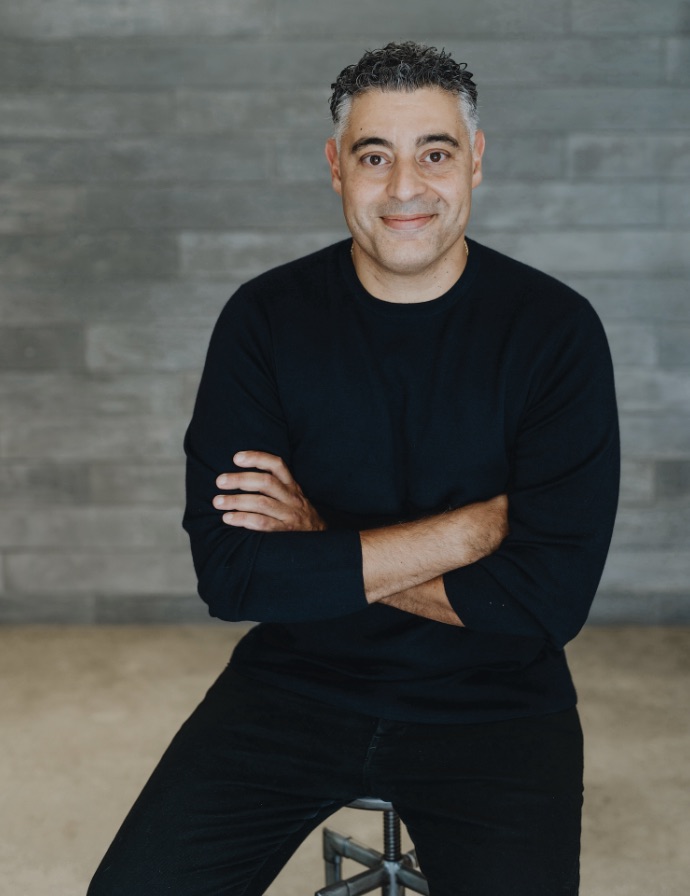 Man smiling in black shirt against gray background