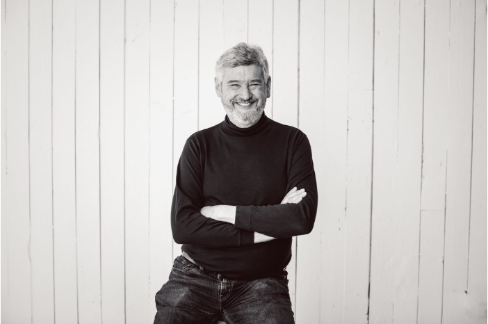 Smiling man in black turtleneck, arms crossed